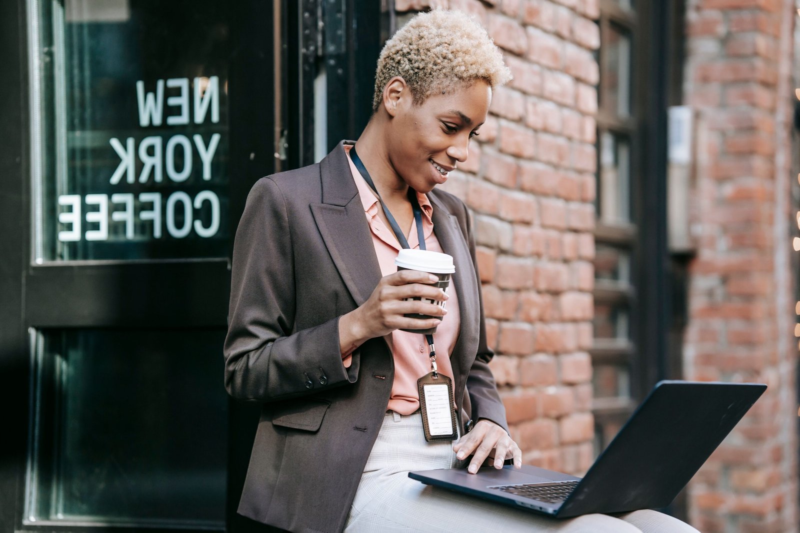 Black Woman with short blond hair smiling at computer with coffee in hand